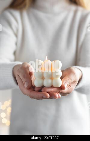 Mani di donna che tengono in mano candele di soia fatte a mano a forma di cubo, primo piano Foto Stock