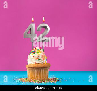 Candela di compleanno illuminata con il numero 42 - biglietto celebrazione su sfondo viola e blu Foto Stock