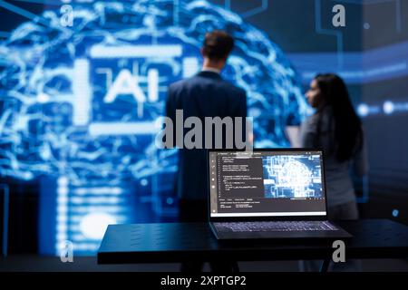 Concentratevi sulla tecnologia di computing cognitivo basata sull'intelligenza artificiale utilizzata dai membri del personale IT in background sfocato. Primo piano del notebook utilizzato dai tecnici del lavoro di squadra per eseguire l'estrazione dei dati con algoritmi di autoapprendimento Foto Stock