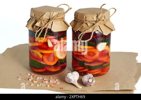 Due vasetti di vetro con verdure fermentate biologiche su sfondo bianco. Carote, zucchine e barbabietole sottaceto fatte in casa Foto Stock