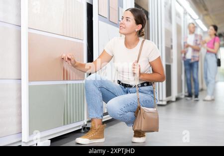 Ragazza che esamina i campioni di piastrelle sul supporto scorrevole nel negozio di articoli per la casa Foto Stock