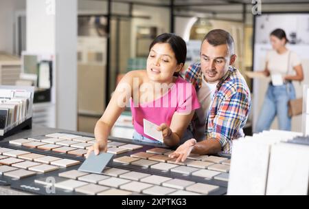 Accoppiare i campioni di piastrelle di navigazione sulla bacheca nel negozio di articoli per il miglioramento della casa Foto Stock