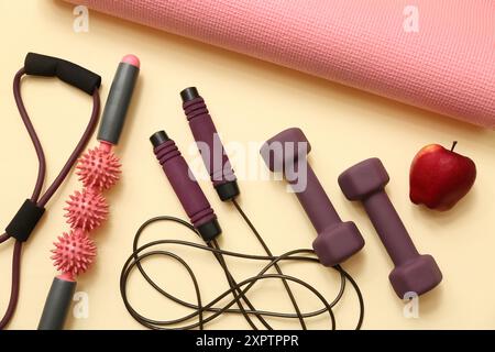 Apple e diverse attrezzature sportive sullo sfondo beige Foto Stock