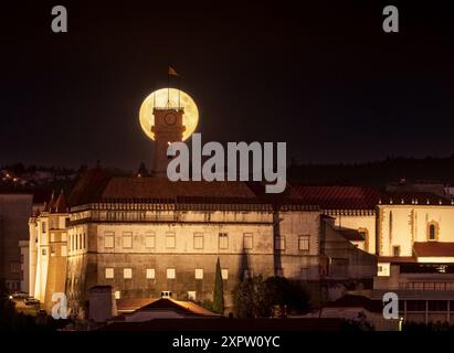 super luna dietro la torre dell'Università di Coimbra in Portogallo. Alba di notte. Foto Stock