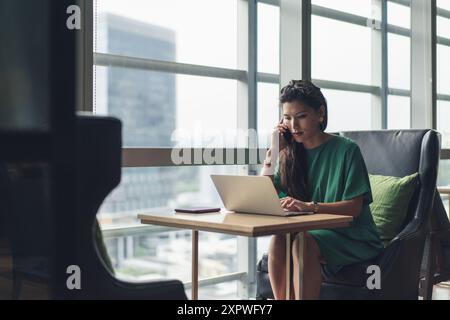 Donna d'affari asiatica hot desking e occupata con il lavoro Foto Stock