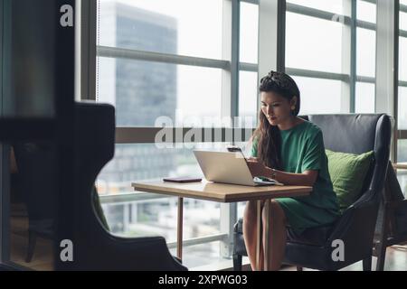 Donna d'affari asiatica hot desking e occupata con il lavoro Foto Stock