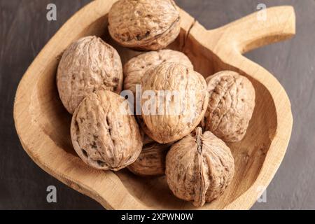 Noci mature non sgusciate nel guscio in una ciotola di legno sagomata. Noci crude non sbucciate. Vista dall'alto. Foto Stock