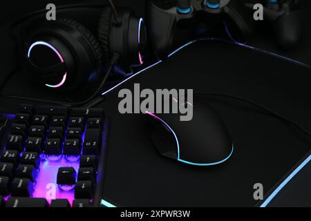 Mouse per computer, tastiera RGB, cuffia e controller di gioco su sfondo scuro, primo piano Foto Stock