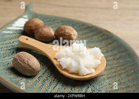 Burro di karitè in cucchiaio e noci su un tavolo di legno, primo piano Foto Stock