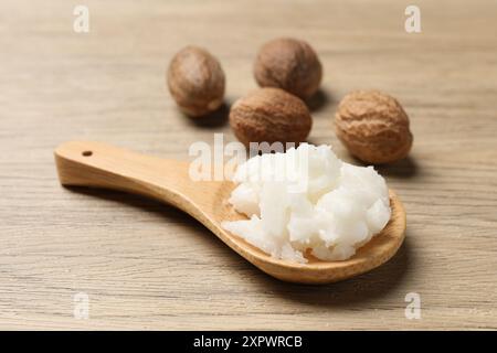 Burro di karitè in cucchiaio e noci su un tavolo di legno, primo piano Foto Stock