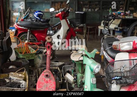 Motocicletta in officina. Vecchio negozio con biciclette e scooter rotti per la riparazione. Servizi e riparazione di motociclette. Foto Stock