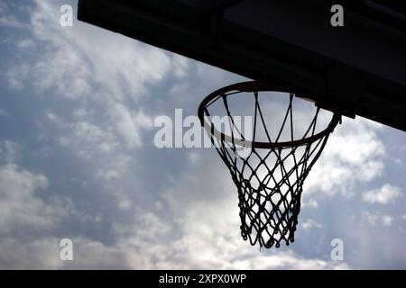 Silhouette di un canestro da basket contro un cielo blu Foto Stock