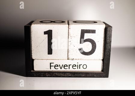 Un calendario perpetuo in legno che mostra il 15 febbraio in portoghese su sfondo bianco Foto Stock