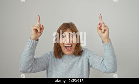 Donna di mezza età eccitata con capelli corti rivolti verso l'alto su sfondo bianco, che esprime sorpresa ed entusiasmo. Foto Stock