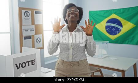 Donna che festeggia nella sala delle votazioni con sfondo della bandiera brasiliana e materiali elettorali visibili Foto Stock