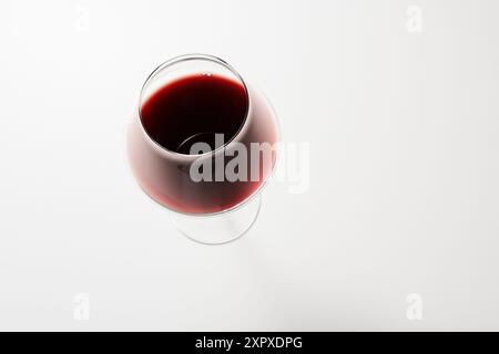 Vista dall'alto della bevanda rossa versata nel bicchiere di vino bianco. Foto Stock