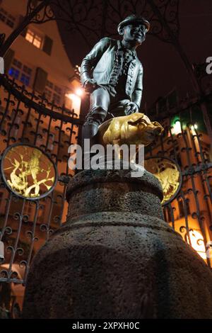 Prima rotata di una figura ornata di fontana in bronzo di notte a Stoccarda, Germania, incorniciata da una gabbia in ferro battuto. Foto Stock