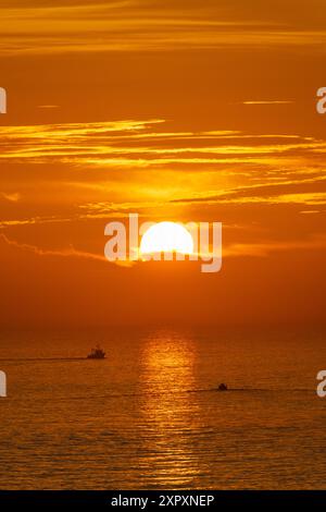 Due barche da pesca salpano al tramonto fuori dal Ría de Pontevedra in Galizia al tramonto, con il sole che tramonta sullo sfondo. Foto Stock