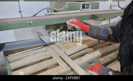 Primo piano del lavoratore tagliando e planando con cura pezzi di legno per mobili nell'industria del legno Foto Stock