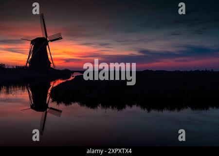 Mulino a vento olandese su un canale alla luce del mattino presto, Paesi Bassi, Frisia, Hempenserpolder, Leeuwarden Foto Stock