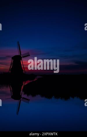 Mulino a vento olandese su un canale alla luce del mattino presto, Paesi Bassi, Frisia, Hempenserpolder, Leeuwarden Foto Stock