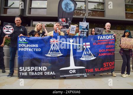 I manifestanti tengono uno striscione che invita il Regno Unito a sospendere gli accordi commerciali con le Isole Faroe per la continua macellazione dei delfini, durante la manifestazione. I manifestanti si sono riuniti fuori dall'ambasciata danese a sostegno dell'attivista anti-baleniera Paul Watson, fondatore del gruppo di conservazione Sea Shepherd. Watson è stato arrestato in Groenlandia e sta affrontando in Giappone l'accusa di complice di aggressione e di violazione delle navi, il che lo ha visto ottenere una pena detentiva di 15 anni. (Foto di Vuk Valcic / SOPA Images/Sipa USA) Foto Stock