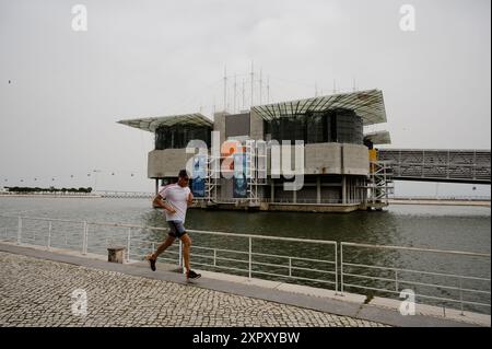 Il jogger passa accanto all'iconico Oceanarium di Lisbona, lungo il fiume Tago. Foto Stock