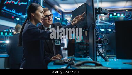 Diversi operatori di sesso femminile e maschile che analizzano dati finanziari in tempo reale e report sullo stato del mercato finanziario. Professionisti di Borsa che discutono di opzioni di acquisto o vendita per diverse obbligazioni Foto Stock