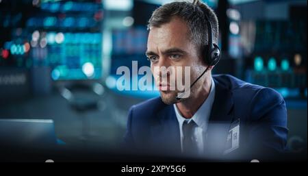 Ritratto di un analista finanziario che utilizza un computer desktop con grafici in tempo reale, report finanziari e aggiornamenti di mercato. Trader che lavora in una moderna Borsa e comunica con i broker Foto Stock
