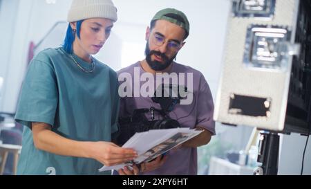 Giovani cinegrafi caucasici e maschi mediorientali recensiscono Una sceneggiatura di Una camera su Un set cinematografico occupato, concentrandosi sulla produzione di video per Un documentario o uno spettacolo televisivo. Foto Stock