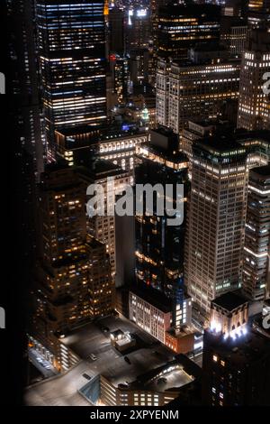 Vista aerea notturna delle strade di New York City a Manhattan con parcheggio sul tetto dell'edificio residenziale per auto. Vista in elicottero di una grande città durante la notte Foto Stock