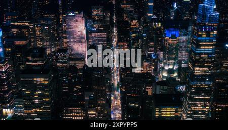 Riprese aeree notturne cinematografiche che catturano la vita notturna di New York. Elicottero. Vista dall'alto in basso sulle strade della città con auto e taxi, pedoni su Crossroads, Bike Messengers sulle corsie degli autobus Foto Stock