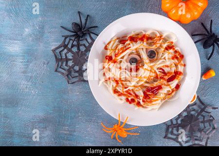 Cibo divertente per bambini per il pranzo o la cena di Halloween. Spaghetti con salsicce, ricetta creativa sotto forma di mummie con ketchup fatto di sangue, con Hallowe Foto Stock