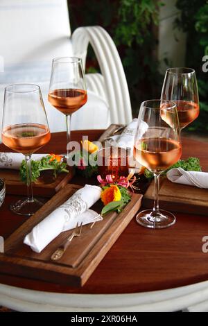 Tavolo meravigliosamente allestito con bicchieri di vino rosato, posate e tovaglioli nella terrazza del ristorante all'aperto in Svezia. Foto Stock