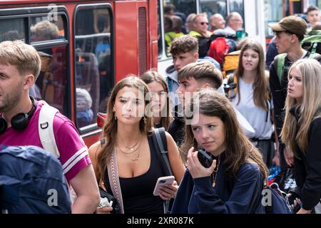 Alcuni dei 1400 giovani entusiasti fanno la fila pazientemente dopo essere arrivati su un treno alla stazione ferroviaria di Newquay per il Boardmasters Festival di Newquay Foto Stock