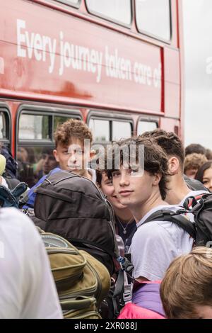 Alcuni dei 1400 giovani entusiasti fanno la fila pazientemente dopo essere arrivati su un treno alla stazione ferroviaria di Newquay per il Boardmasters Festival di Newquay Foto Stock