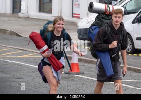 Giovani in arrivo; trasportano la loro attrezzatura da campeggio in cerca di autobus per portarli al Boardmasters Festival di Newquay, in Cornovaglia, nel Regno Unito. Foto Stock