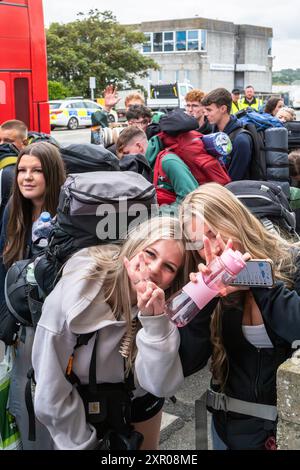 Alcuni dei 1400 giovani entusiasti fanno la fila pazientemente dopo essere arrivati su un treno alla stazione ferroviaria di Newquay per il Boardmasters Festival di Newquay Foto Stock