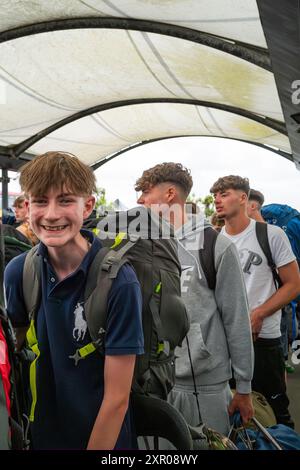 Giovani entusiasti che arrivano alla stazione ferroviaria di Newquay e fanno la fila per salire a bordo degli autobus per portarli al Boardmasters Festival Newquay in Cornovaglia Foto Stock