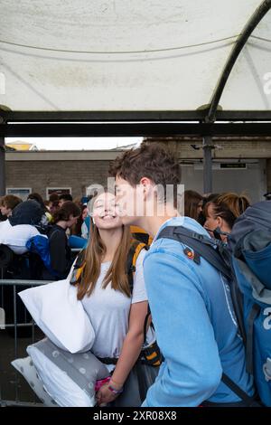 Giovani entusiasti che arrivano alla stazione ferroviaria di Newquay e fanno la fila per salire a bordo degli autobus per portarli al Boardmasters Festival Newquay in Cornovaglia Foto Stock