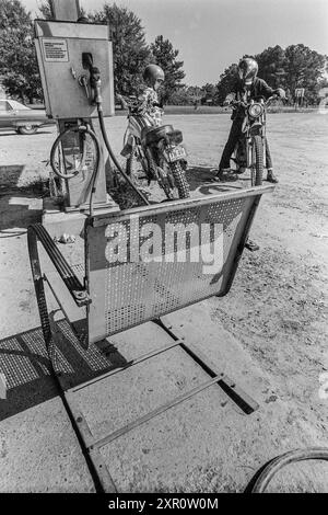 Macedonia, Arkansas, Stati Uniti – 23 giugno 2024: Ripresa verticale di due adolescenti su moto da terra che chattano dopo aver acquistato benzina nel 1975. Foto Stock