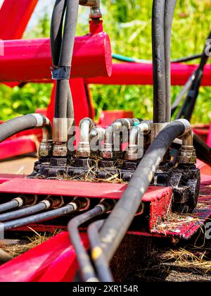 Primo piano di tubi flessibili idraulici industriali collegati a macchinari in un campo Foto Stock