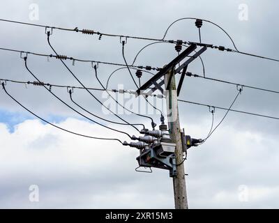 Linee elettriche e trasformatori su un'asta di legno contro un cielo nuvoloso. Hope Valley, Derbyshire, Regno Unito. Foto Stock