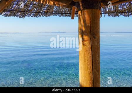 Uno di paglia ombrellone in spiaggia al mare blu Foto Stock