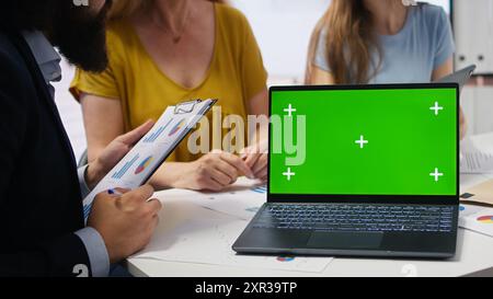 Clienti che cercano una guida personalizzata alla pianificazione su un notebook con schermo verde scritta dal consulente finanziario durante la riunione. Consulente che ottimizza le spese di vita per i clienti utilizzando un notebook mockup, una fotocamera A. Foto Stock