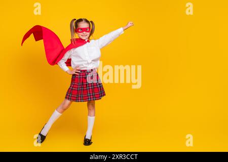 Ritratto completo del corpo dell'uniforme del costume da supereroe della piccola studentessa spazio vuoto isolato su sfondo giallo Foto Stock