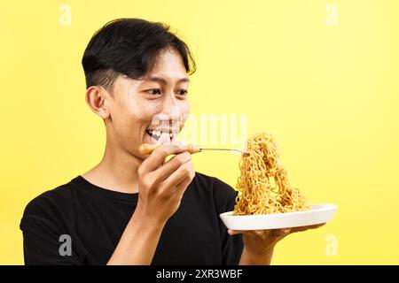 Indonesiano giovane che mangia Indomie Fried Noodle, Happy Face Foto Stock