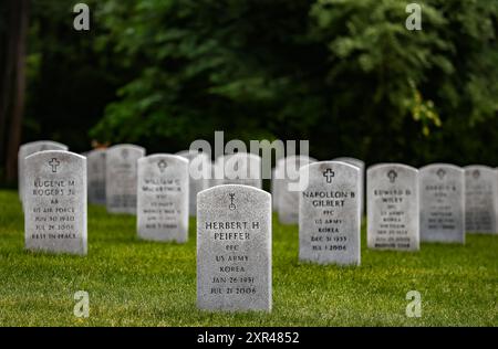 Un solenne tributo: File di lapidi bianche in un cimitero militare, in onore degli uomini e delle donne coraggiosi che hanno servito il loro paese. Foto Stock