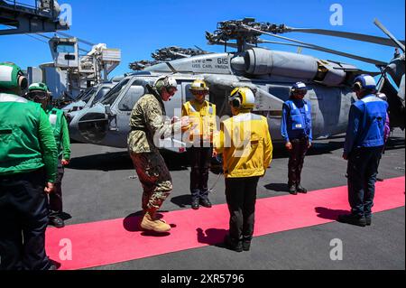 Vice Adm. John Wade, comandante della 3rd Fleet degli Stati Uniti, ed Exercise Rim of the Pacific (RIMPAC) 2024 Combined Task Force Commander, saluta i marinai sul ponte di volo della portaerei classe Nimitz USS Carl Vinson (CVN 70) mentre la nave partecipa alla fase di integrazione della forza del RIMPAC 2024, 20 luglio. Ventinove nazioni, 40 navi di superficie, tre sottomarini, 14 forze terrestri nazionali, più di 150 aerei e 25.000 personale partecipano al RIMPAC nelle e intorno alle isole Hawaii, dal giugno 27 al agosto 1. Il RIMPAC, la più grande esercitazione marittima internazionale del mondo, offre un'operazione di formazione unica Foto Stock