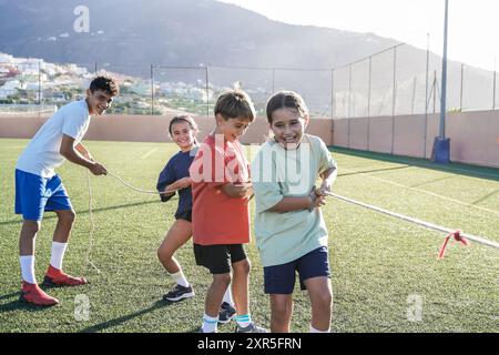 Sport, gruppo di bambini che giocano a tiraggio di corda nel campo di calcio scolastico. I bambini si divertono durante l'allenamento Foto Stock